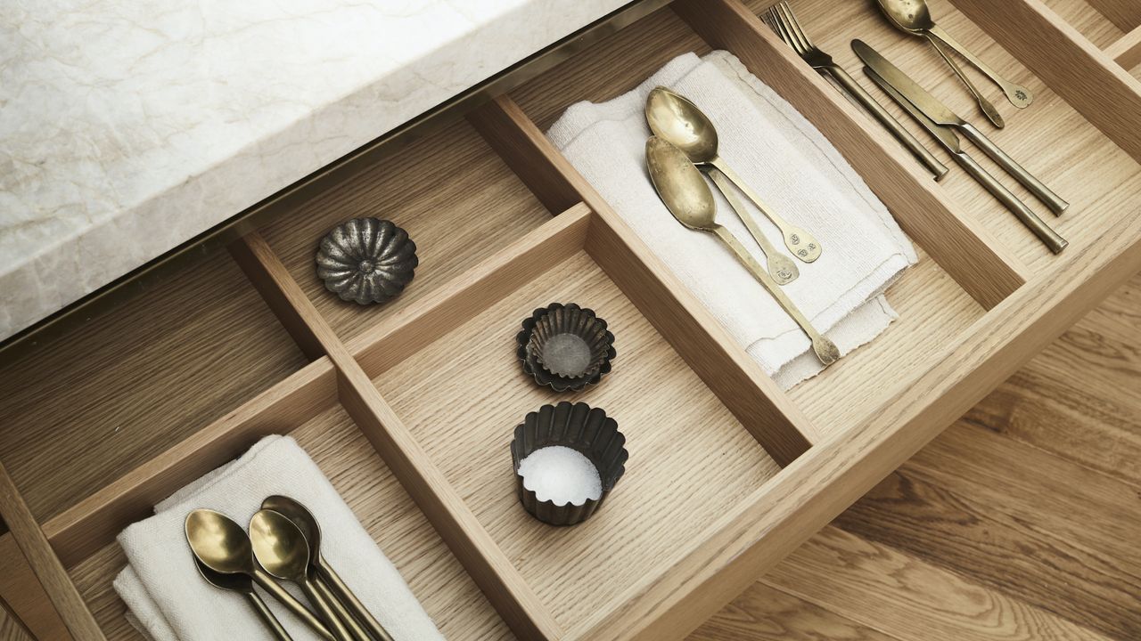 inside of an oak veneered kitchen drawer with utensils.