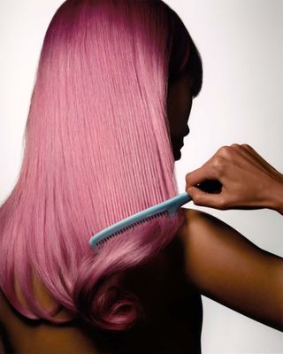 Close-up shot of a woman combing her pink hair