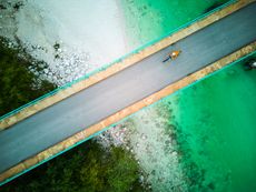 A lone cyclist rides across a bridge over a river