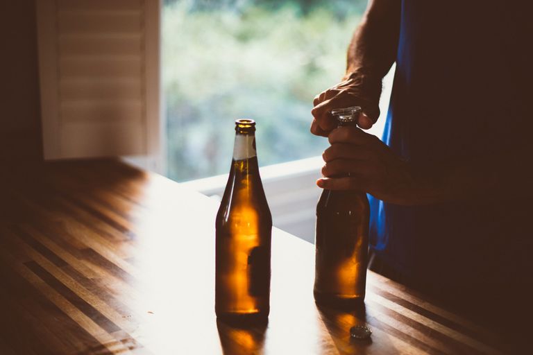 Person opening a bottle of beer after having Covid-19 vaccine