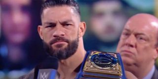 Roman Reigns holding his belt and looking angry while speaking into the microphone on Smackdown.