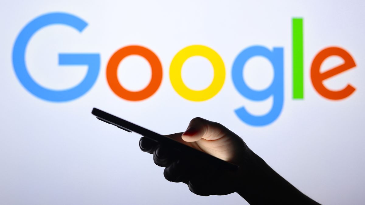 A phone in hand in front of a Google logo