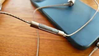 SoundMagic E80D wired in-ear headphones looped on blue smartphone case