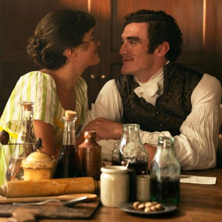 Ella Bruccolerias Mary Bennet and Hayward D&oacute;nal Finnas as Tom Hayward smiling at each other over a kitchen table in the other bennet christmas special