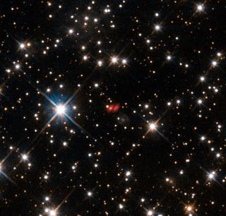 This image from the NASA/ESA Hubble Space Telescope shows the distant active galaxy PKG 1830-211. It shows up as an unremarkable looking star-like object, hard to spot among the many much closer real stars in this picture. Recent ALMA observations show both components of this distant gravitational lens and are marked in red on this composite picture. Image released Oct. 16, 2013.