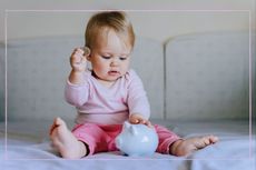 A baby girl putting a coin into a piggy bank