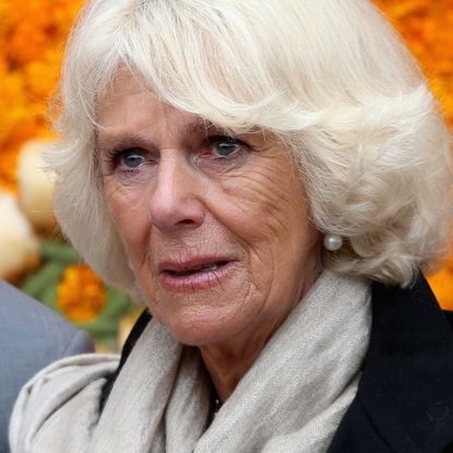 Queen Camilla has blonde coiffed hair and has tears in her eyes