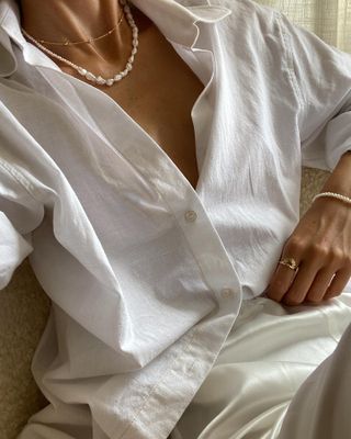 Woman wears white shirt, slip skirt, pearl necklace