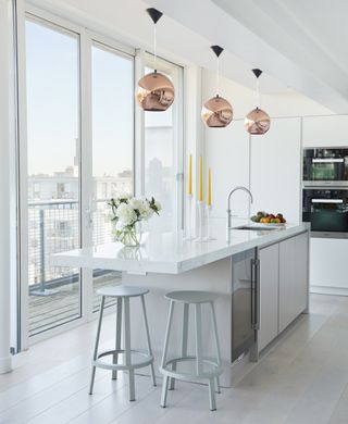 Modern, white kitchen with brass light shades