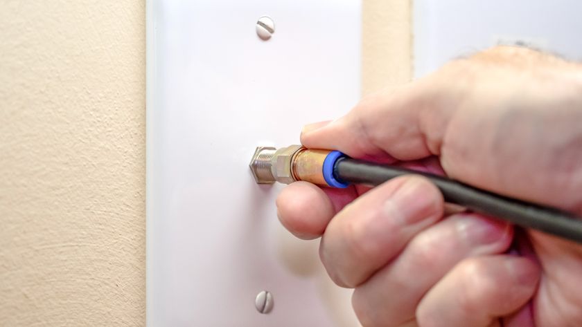 A person plugging a coaxial cable into the wall