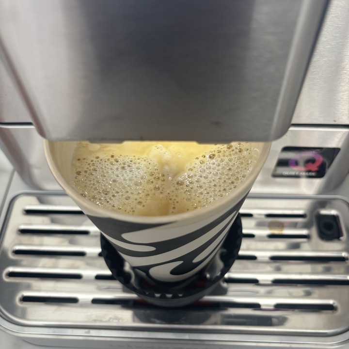 The KitchenAid Fully Automatic Espresso Machine KF8 making a plant-based latte in a travel mug.