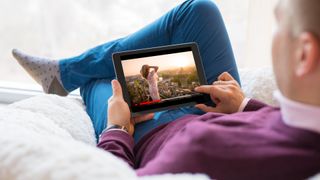 Man lying on a beanbag holding a tablet which is playing a video