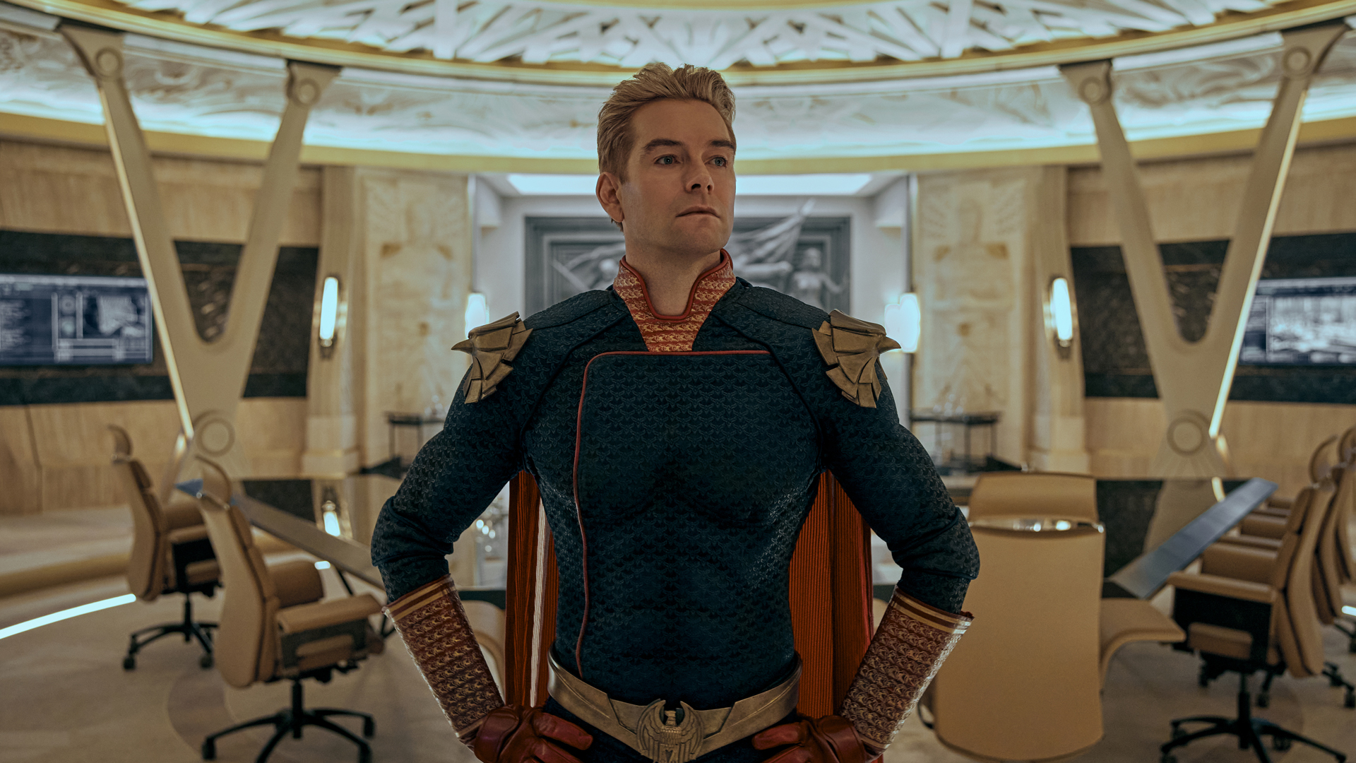 Homelander stands proud with his hands on his hips in Vought's main conference room in The Boys season 3