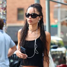 Zoe Kravitz in NYC wearing a black tank, knee-length slip skirt, and high-foot ballet flats.