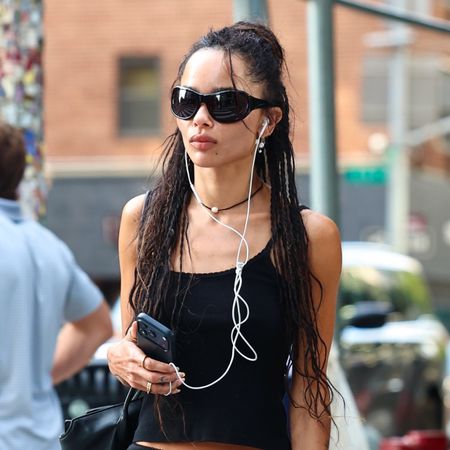 Zoe Kravitz in NYC wearing a black tank, knee-length slip skirt, and high-foot ballet flats.