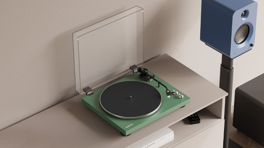 Kanto Audio Obi3 turntable in green on a light colored shelf next to a light blue Kanto speaker