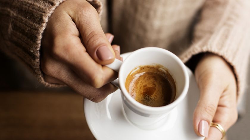 Woman's hands holding cup of espresso coffee
