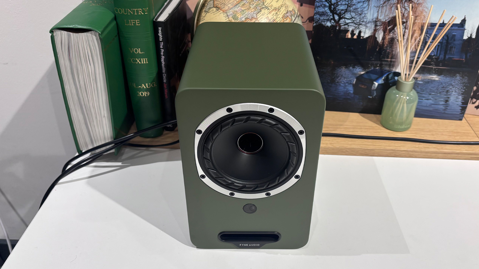 Fyne Audio Cubitt 5 speakers in olive green finish, placed on white table with records in background