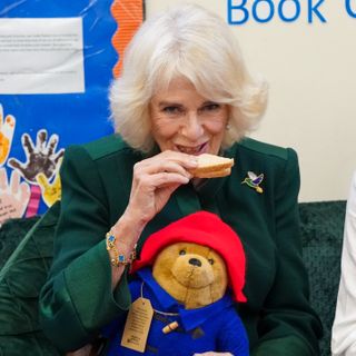 Camilla, Queen Consort eats a sandwich as she attends a special teddy bears picnic at a Barnardo's Nursery in Bow on November 24, 2022 in London, England.