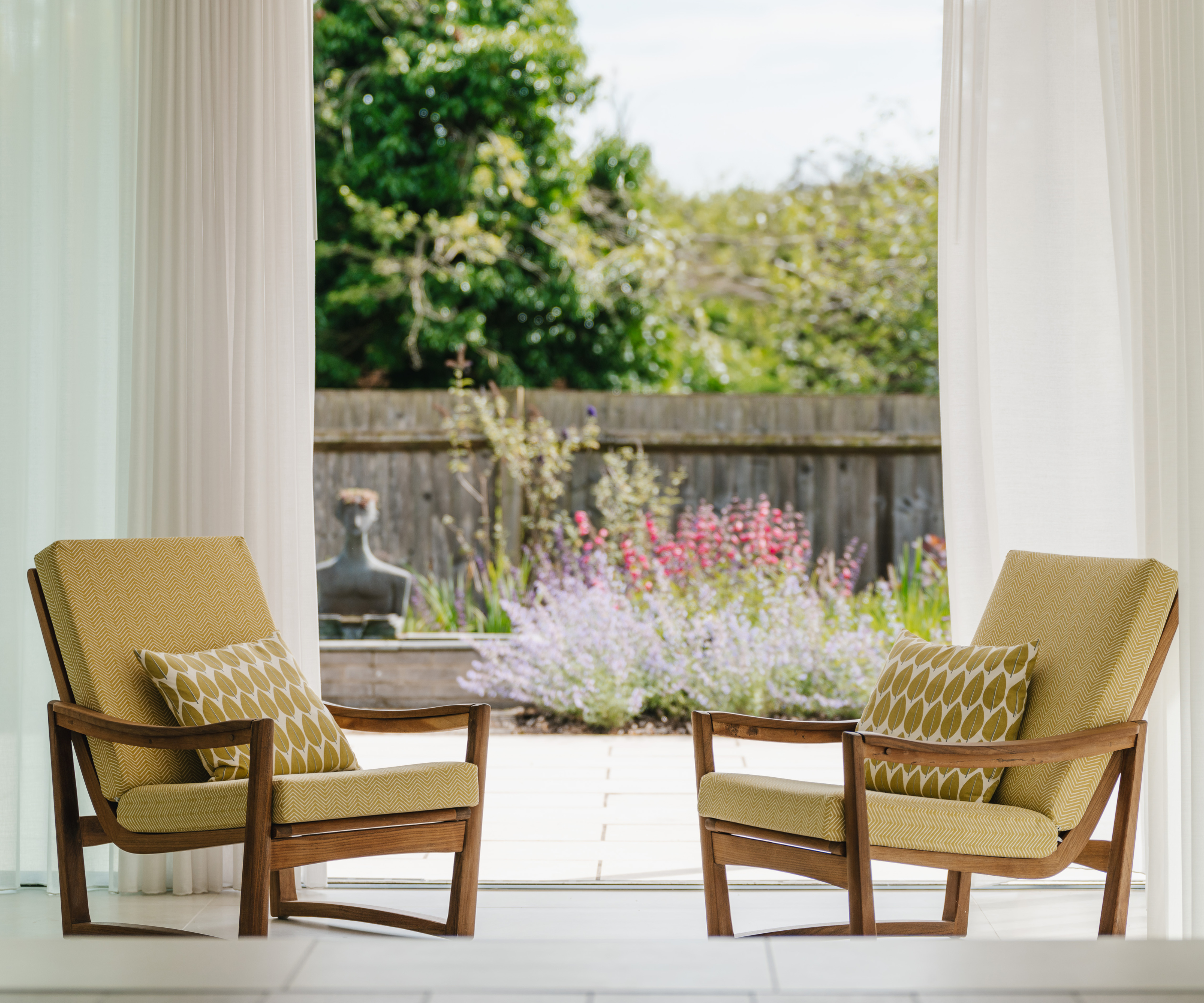 two chairs next to a window that overlooks the garden with flowers