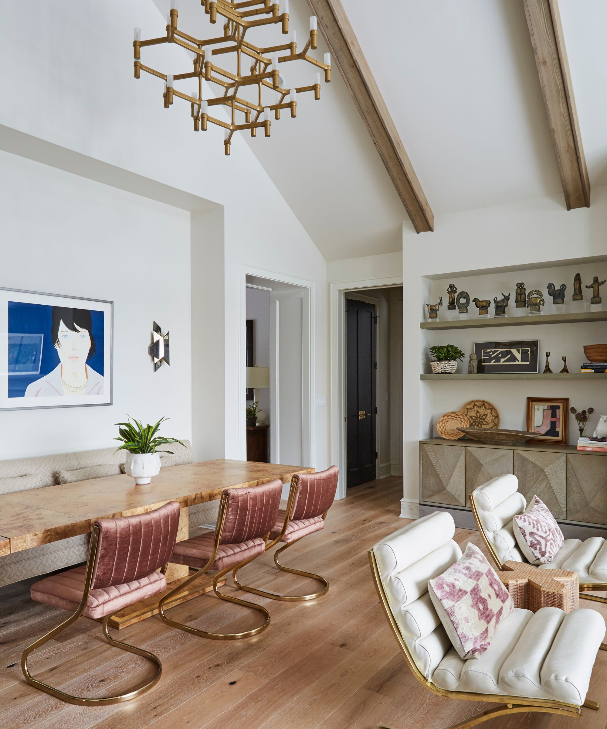 A modern open plan living and dining space with reupholstered white and wood antique chairs