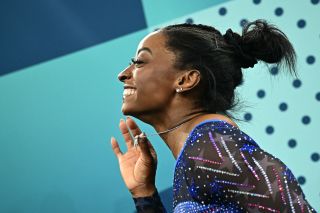 Simone Biles after winning her gold medal holding up her goat necklace