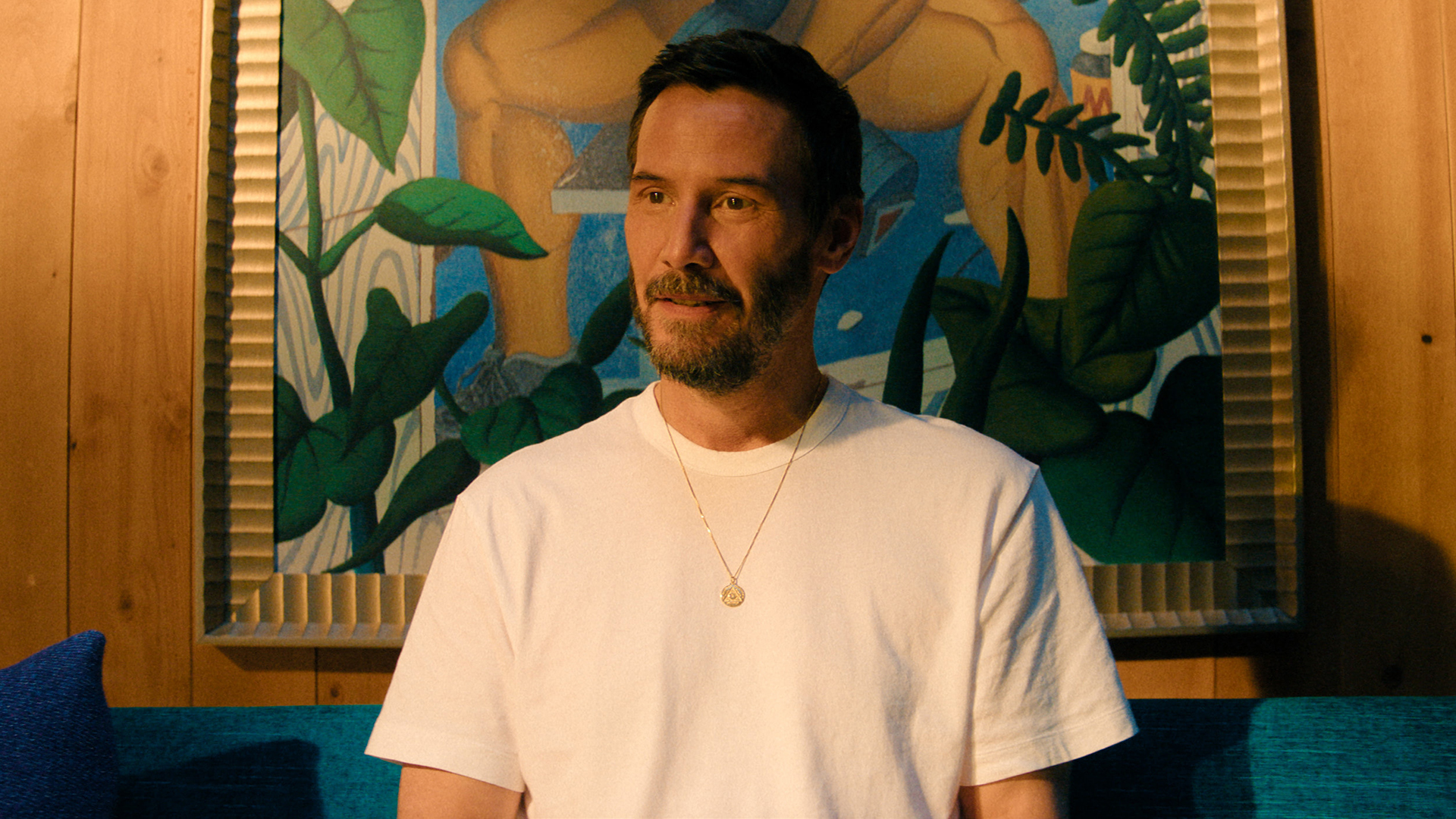 Keanu Reeves' Reef sitting on a couch in Apple TV's Outcome movie