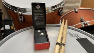 Open box of Vibes Hi Fidelity Earplugs on a snare drum next to a pair of drumsticks