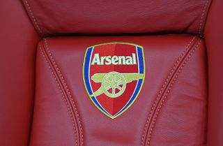 The Arsenal badge on a red seat in the dugout at the Emirates Stadium