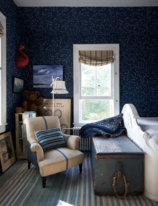 bedroom with dark blue constellation wallpaper and armchair with striped linen cover
