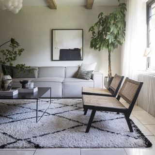 Monochrome berber rug in a living room with grey sofa and rattan chair.