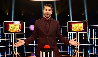 In With a Shout season 2 host Joel Dommett posing next to a buzzer