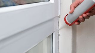 person caulking window seal