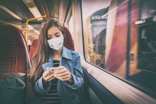 A person riding a train wearing a face mask.