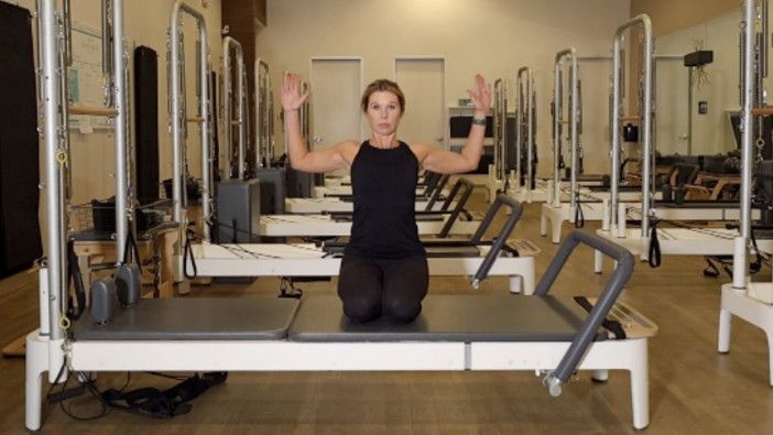 Woman on a Reformer Pilates machine demonstrating an exercise