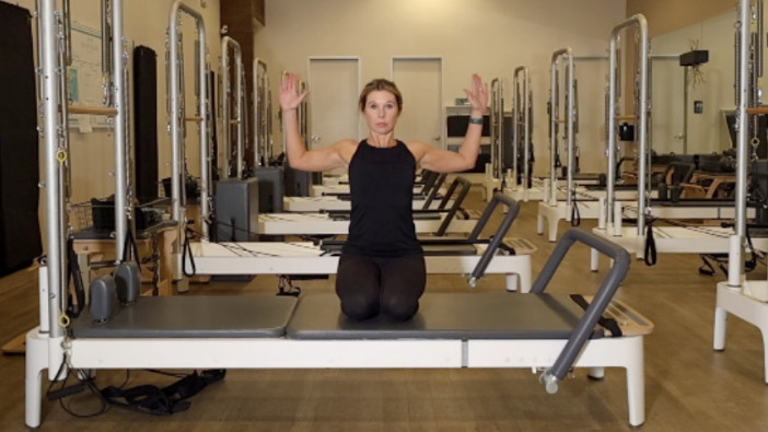 Woman on a Reformer Pilates machine demonstrating an exercise