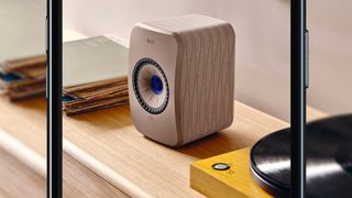 The KEF II LT stereo speaker on a bench framed by an iphone 