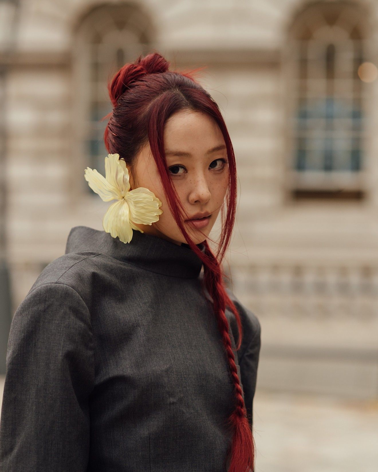 a model with red hair in a top knot poses for a portrait.