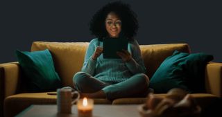 坐在沙發上閱讀電子平板電腦的女人
