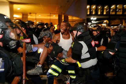A seriously injured protester is carried to safety Wednesday night in Charlotte.