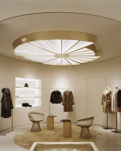 Fur coats hanging on clothing rails in a boutique with white recessed wall shelves and white walls