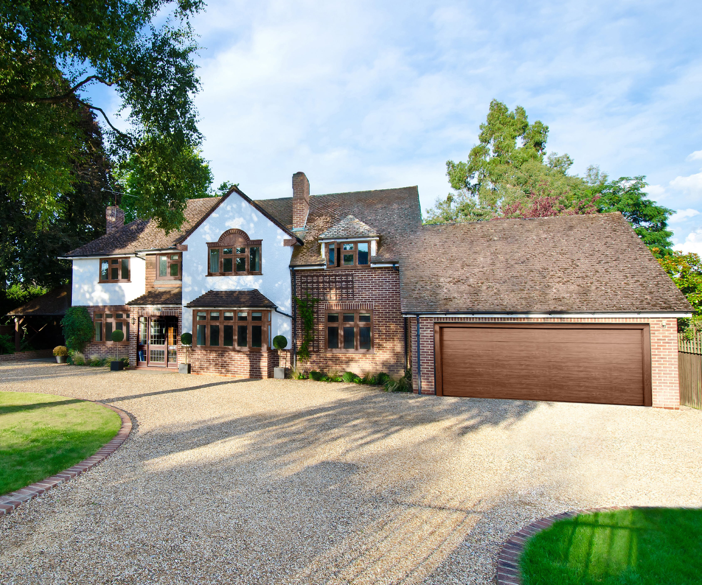 old period property with gravel driveway leading to house and large garage