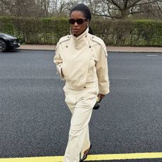 Marilyn wears a cropped trench coat and beige pants.