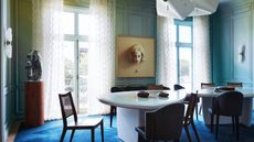 Dining room with ombre yellow-green and aqua walls, cobalt carpet and wood chairs and table