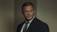 Reacher in suit standing in interrogation room in Reacher Season 2