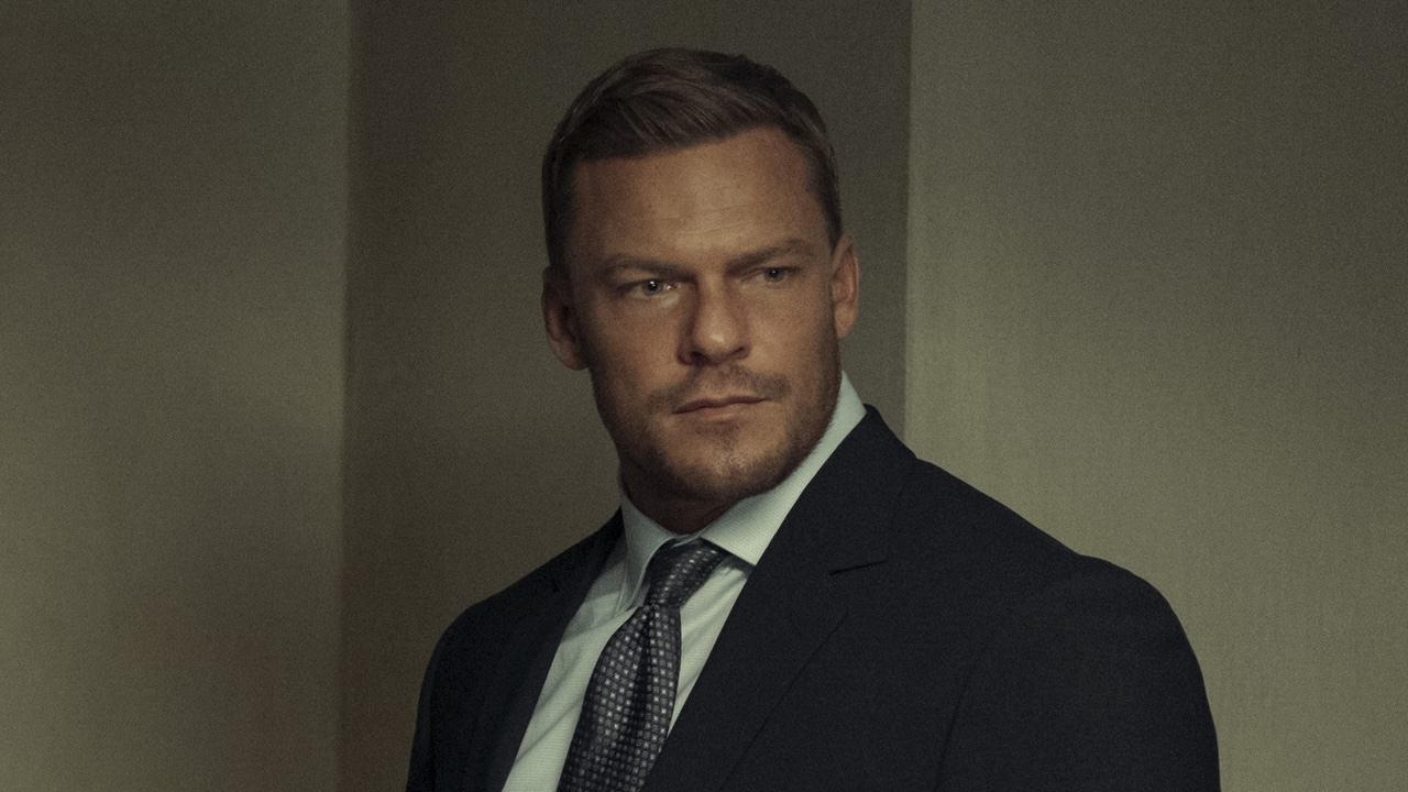 Reacher in suit standing in interrogation room in Reacher Season 2