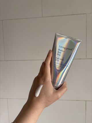 Mica Ricketts showing swatch of Living Proof Perfect Hair Day High-Shine Gloss on back of hand