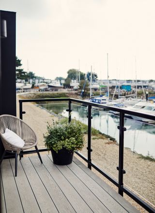 outside deck with round basket chair and view of marina from glass balcony