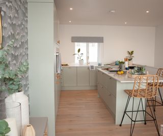 A kitchen with sea green cabinets and engineered wood flooring