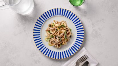 smoked tagliatelle with brie and asparagus served on a blue and white plate